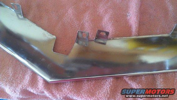 Chrome trim piece with mounting tabs, resting on a pink cloth