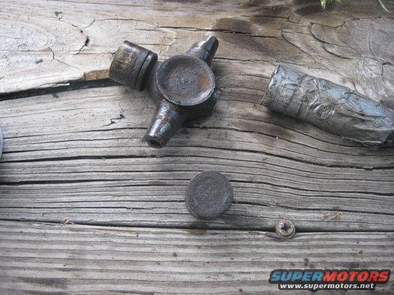 Close-up of a universal joint and a piece of a driveshaft on a wooden surface