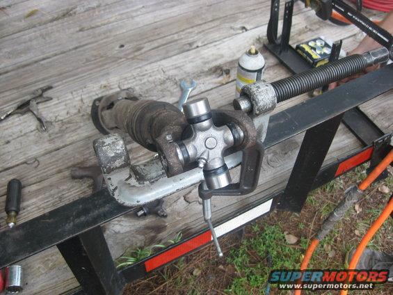 Driveshaft universal joint clamped in a vise on a wooden trailer deck