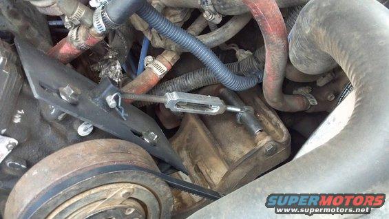 I picked up a swivel eye rod with a 5/16 eye and a 5/16-18 thread.  I matched it to a 5/16 turnbuckle from the local hardware store.  I got a short piece of 1" square tube, drilled a 5/16 hole in it, and welded it to my bracket. A 5/16 clevis pin anchors the upper end, and I drilled out the eye bolt on the lower end to 3/4, which was just large enough for that piece of round tube to slide in. 

Twisting the turnbuckle adjust tension, and pulled the clevis pin lets me easy remove the belt if needed.