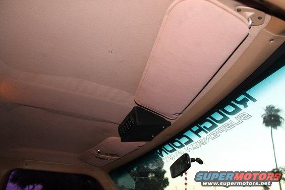 Interior shot of a vehicle showing the headliner, sun visor, and a black overhead accessory. A sticker on the windshield reads "ROUGH COUNTRY SUSPENSION"