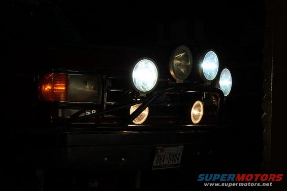 Front of a vehicle with multiple bright auxiliary lights mounted on a bar above the grille. Headlights and turn signals are visible
