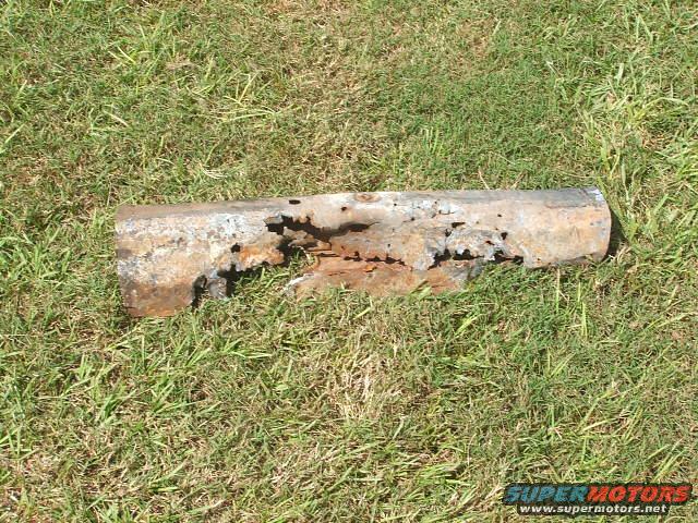 Heavily rusted metal pipe fragment lying on grass