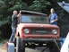 1966 International Scout 800 - A red International Scout is being loaded onto a trailer with assistance from two people.