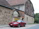 2003 Mercury Marauder - This red 2003 Ford Mustang coupe is parked on a cobblestone street in front of a historic building.