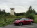 2003 Mercury Marauder - Red Ford Mustang parked near an old watchtower in a rural area.