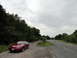 2003 Mercury Marauder - A red coupe sits parked on a gravel shoulder next to a road with trees in the background.