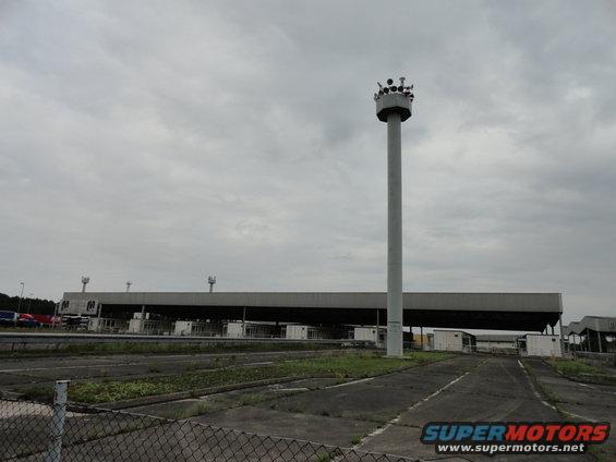 toll plaza with a tall tower topped with lights, under a cloudy sky