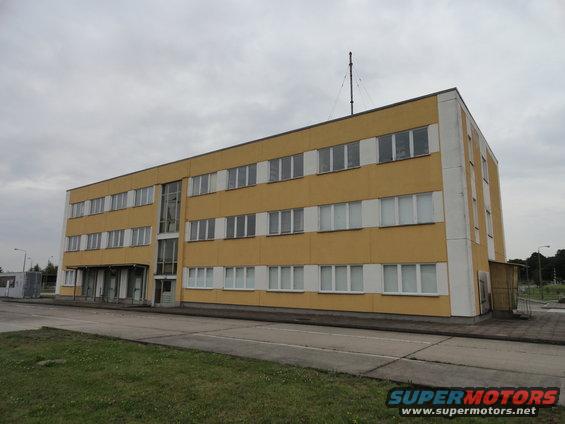 Yellow industrial building with antenna against a cloudy sky