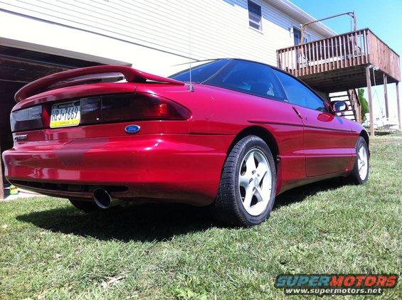 Red 1994 Ford Probe rear view, parked on grass with a house in background