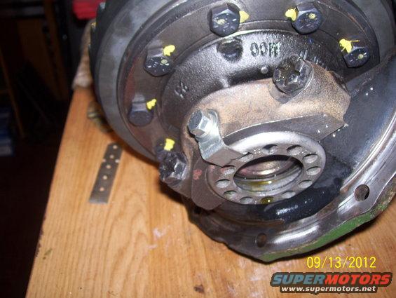 Differential housing with bolts and yellow markings on a wooden surface