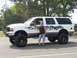 2001 Ford Excursion - A man poses with his heavily modified Ford Excursion, a significant lift kit and custom decals.