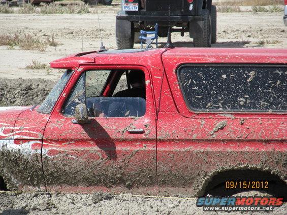 Red 1979 Ford Bronco stuck in mud, side view