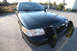 2004 Ford Crown Victoria - Black Ford Crown Victoria police car with push bumper is parked outside.