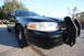 2004 Ford Crown Victoria - A black 2004 Ford Crown Victoria P71 police car is parked on a street, viewed from the front corner.