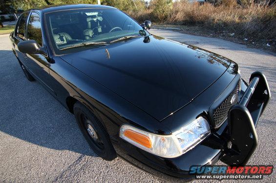 Black 2004 Ford Crown Victoria police car, front 3/4 view, with a push bar and spotlight
