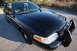 2004 Ford Crown Victoria - This black 2004 Ford Crown Victoria police car is viewed from the front three-quarter angle, showing its push bar and spotlight.