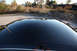 2004 Ford Crown Victoria - The glossy black roof of a car reflects the surrounding environment, including a train car marked with the TTX logo.