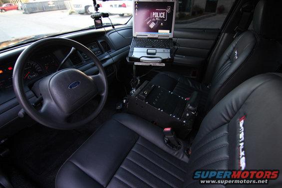 2004 Ford Crown Victoria interior with laptop, police equipment, and black leather seats