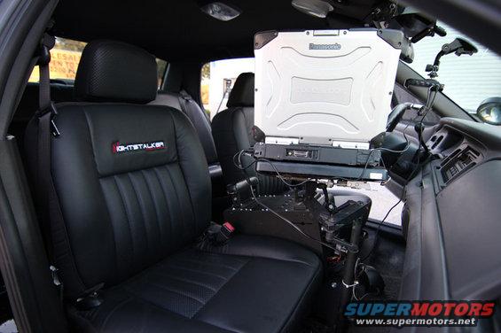 Interior of a police car showing the passenger seat with a 'LIGHTSTALKER' logo and a Panasonic Toughbook laptop mounted on a stand