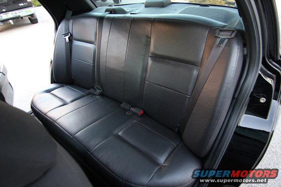 Black leather rear seats with seatbelts inside a car, with a truck visible outside