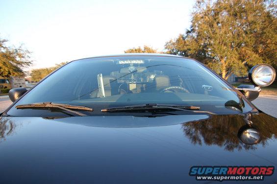 2004 Ford Crown Victoria police car interior, view through windshield showing dashboard, steering wheel, and spotlight