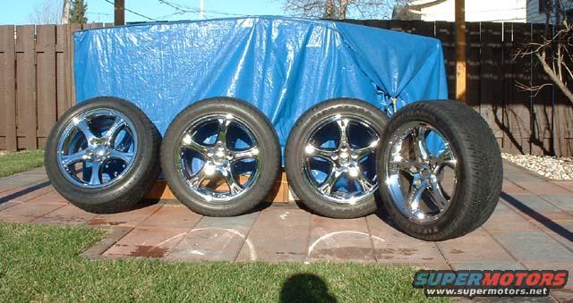 Four chrome wheels with tires on a paved surface
