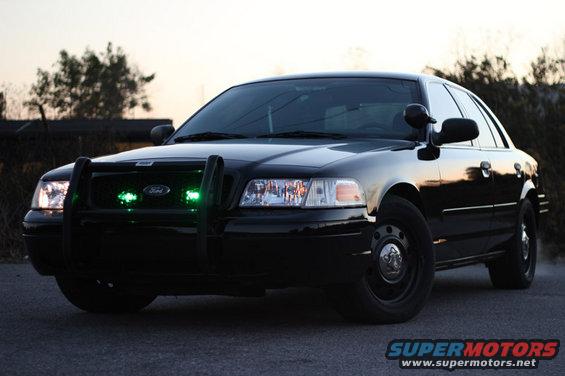 Black Ford Crown Victoria police car with push bar and green lights