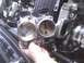 2003 Ford Crown Victoria - Close-up of a hand holding a throttle body, with another throttle body visible in the engine bay.