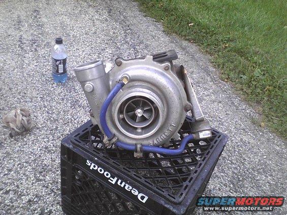Garrett turbocharger sitting on a black milk crate. Bottle of blue liquid and rag nearby