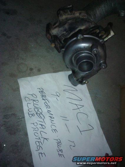 Turbocharger with paper reading 'MAC 1 9-11-12 PERFORMANCE PROBE TALK CLUB PROTEGE'