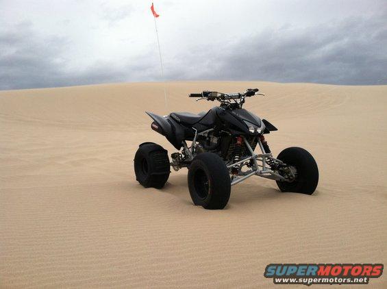 Black 2005 Honda TRX 450 R ATV on sand dunes with a red flag