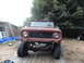 1961 International Scout 80 - Front view of a red 1961 International Scout 80 on a trailer, parked outdoors with trees and a building behind it.