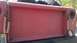 1961 International Scout 80 - Close-up of a red truck's tailgate, showing the International Harvester logo embossed in the center.
