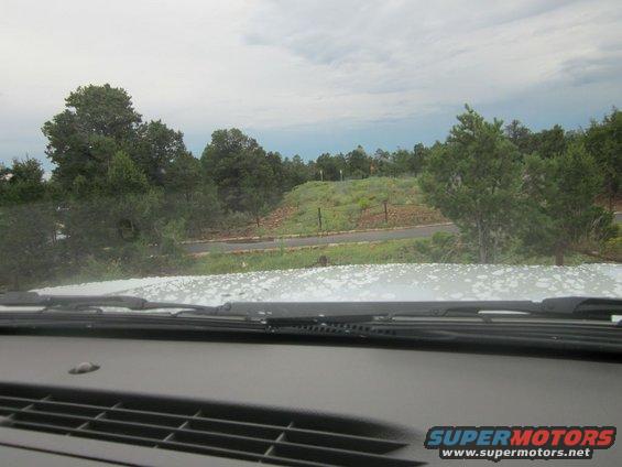 Interior view from a car looking out at a landscape with trees and a cloudy sky