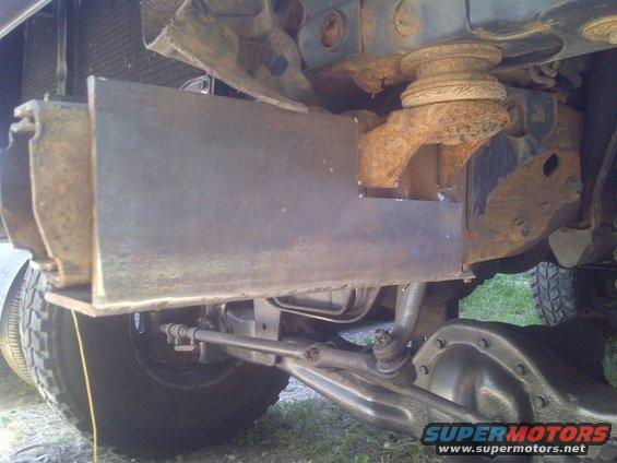Close-up of custom metal plate welded to vehicle frame near front axle and tire