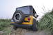 2004 Jeep TJ - Rear view of a yellow 2004 Jeep TJ parked on a grassy incline, a spare tire on the tailgate.