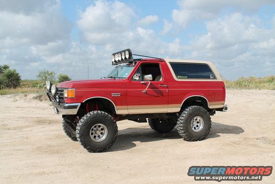 Red lifted 1990 Ford Bronco with off-road lights on roof and bumper