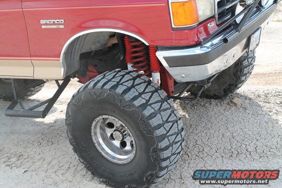 Red 1990 Ford Bronco with lifted suspension and large off-road tires