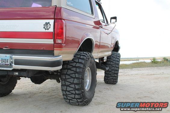 Red 1990 Ford Bronco rear view with large off-road tires