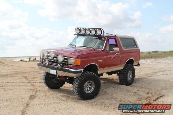 1990 Ford Bronco lifted with off-road lights on sandy terrain