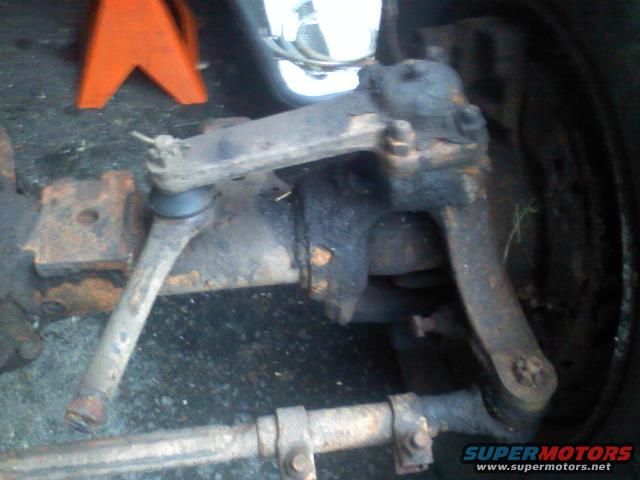 Dana 60 axle with tie rod and ball joint visible, rusty, under orange jack