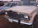 1988 Ford Bronco - Front view of a 1984 Jeep Grand Wagoneer, parked next to a silver sedan.