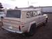 1988 Ford Bronco - A tan Jeep Wagoneer is parked on dirt ground with a white vehicle in the background.