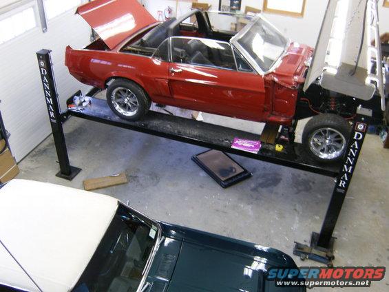 Red convertible car on a four-post lift with hood and trunk open, showing interior and engine bay