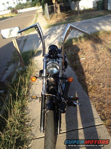 Motorcycle front end with chrome ape hanger handlebars and a round headlight