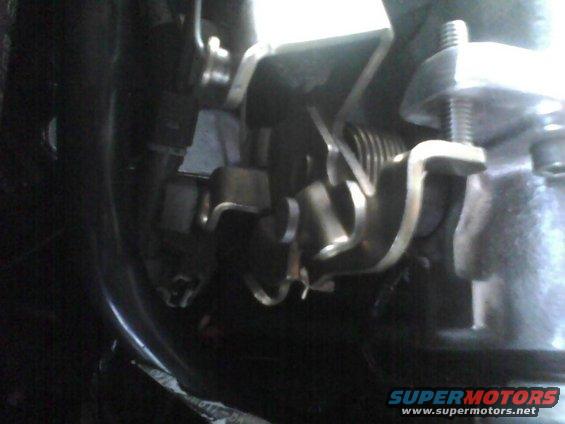 Close-up of a metal throttle linkage with springs and bolts