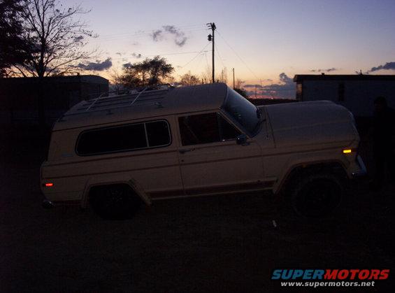 1974 full-size SUV with a camper shell, side view at dusk