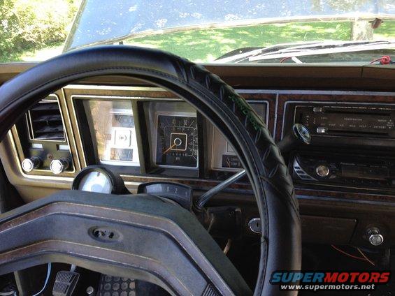 1979 Ford Bronco interior dashboard with wood grain trim, a black steering wheel, and analog gauges