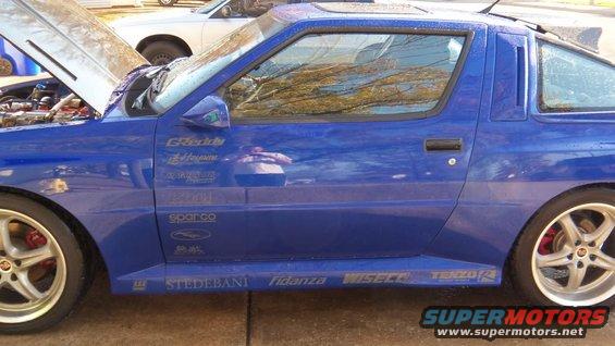 Blue 1989 Mitsubishi Starion with racing decals on the side, hood open, another car in background